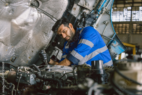 Hispanic Latin Indian Male Mechanic Repairing Truck Engine In Auto Service Garage Workshop.