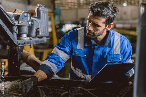 Hispanic Latin Indian Male Mechanic Repairing Truck Engine In Auto Service Garage Workshop.