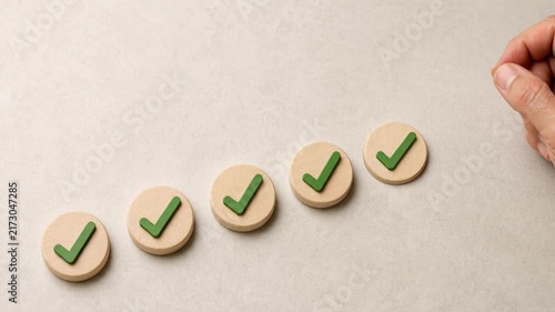 Hand arranging wooden tokens with green check marks symbolizing success progress and achievement