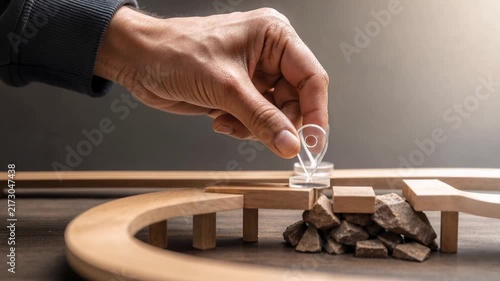 Hand placing location marker on wooden bridge model over rocks representing navigation and travel concept