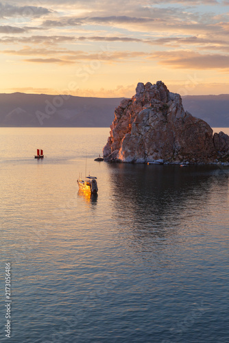 Baikal Lake on a summer evening at sunset. View of silhouette of Shamanka Rock or Cape Burkhan— landmark of Olkhon Island and a popular tourist destination