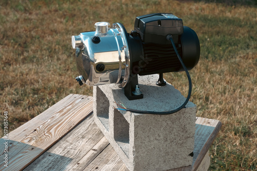 Canvastavla Stainless steel surface water pump mounted on concrete cinder block placed on wo