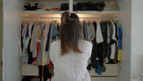 Bild auf Leinwand A woman seen from behind stands with arms crossed, staring into a open white war
