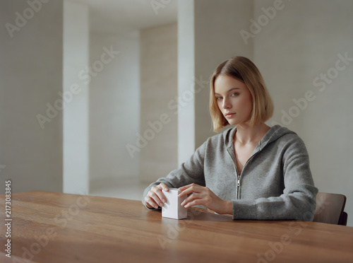 Thoughtful blonde woman contemplating ideas while sitting at a wooden desk in a modern indoor setting