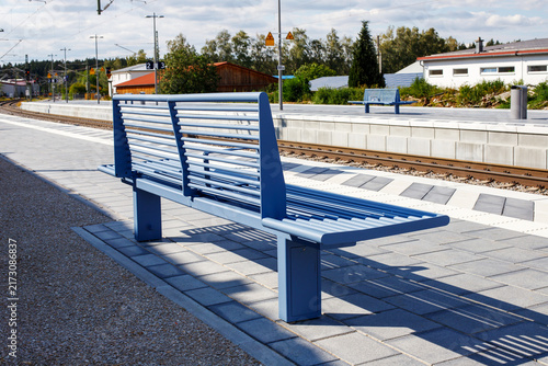 Blue Metal Bench on Railway Station Platform with Train Tracks