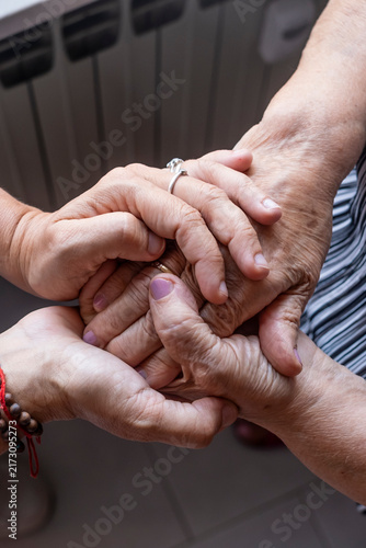 Bild auf Leinwand Young person's hands tenderly holding and comforting an elderly person's wrinkle