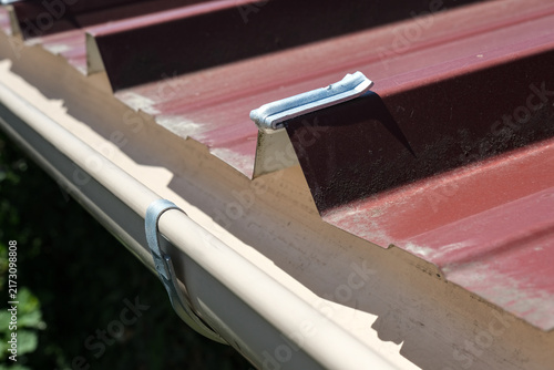 фотографія Galvanized steel gutter fixing bracket mounted on corrugated metal roofing for rainwater drainage installation