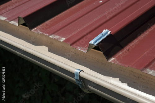 Принти на полотні Galvanized steel gutter fixing bracket mounted on corrugated metal roofing for rainwater drainage installation