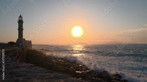 Silhouette of lighthouse in sea at sunset in the city of Chania, island of Crete, Greece. Beautiful seascape at sunset