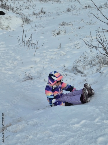 Canvastavla Child in colorful ski suit sledding backwards down a snowy slope