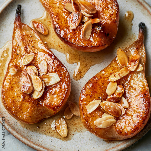 a top view of Roasted pear halves with beautifully caramelized golden surfaces, lightly glazed and topped with toasted sliced almonds