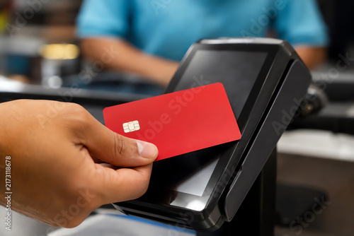 Embracing the future of retail, a customer swiftly completes a purchase with a vibrant red card using contactless technology