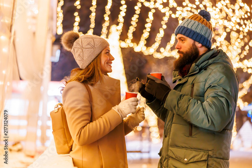 Couple drinking mulled wine while celebrating Christmas outdoors in the city
