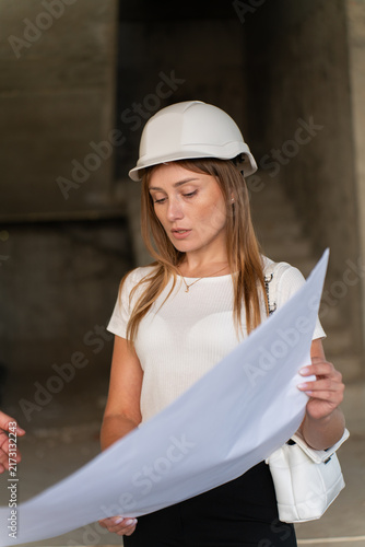 Female engineer examines blueprint holding sheet in hands. Inspector reviews floor plan evaluating drawings preparing to inspect building process