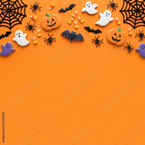 Halloween holiday border with pumpkins ghosts bats spiders and spider webs on a bright orange background for festive party design