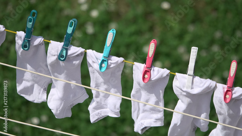 White socks hanging on clothesline with colorful clothespins drying in sunny garden