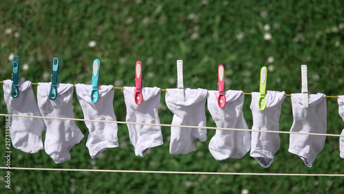 White socks hanging on clothesline with colorful clothespins drying in sunny garden