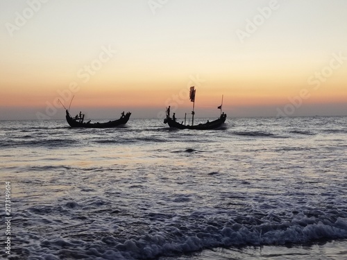 Cuadro en lienzo Traditional crescent Sampan fishing boats silhouetted on ocean waves at sunset i