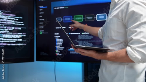 Business professional presenting data insights on digital screen with laptop in modern conference room