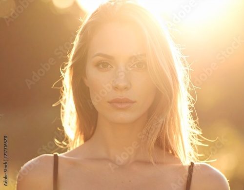 Woman standing confidently with sunlight flare, backlight glow, inspirational mood