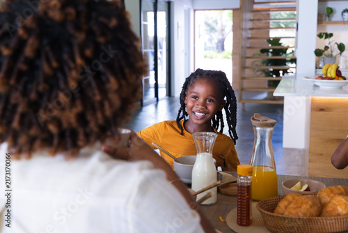African American family sharing breakfast at home, child wearing orange shirt smiling
