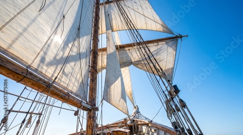Majestic tall ship sails catching the bright sun under a clear blue sky