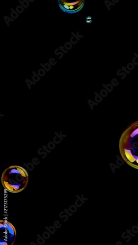Iridescent Soap Bubbles Floating on Black Background. Colorful reflective bubbles drift randomly across deep black with vivid rainbow highlights.