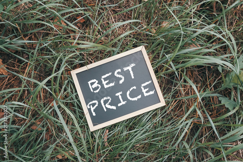 A small chalkboard sign with the words 'Best Price' written in white chalk, placed on a patch of green grass, suggesting a promotional or marketing concept.