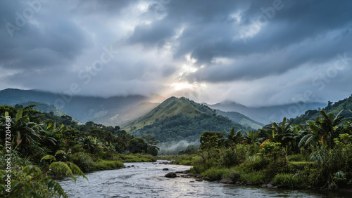 River flowing through lush valley toward majestic green mountain peak under