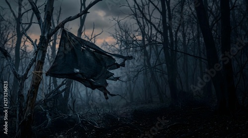 Spooky halloween forest landscape with a tattered flag on a dead tree and plenty of copyspace