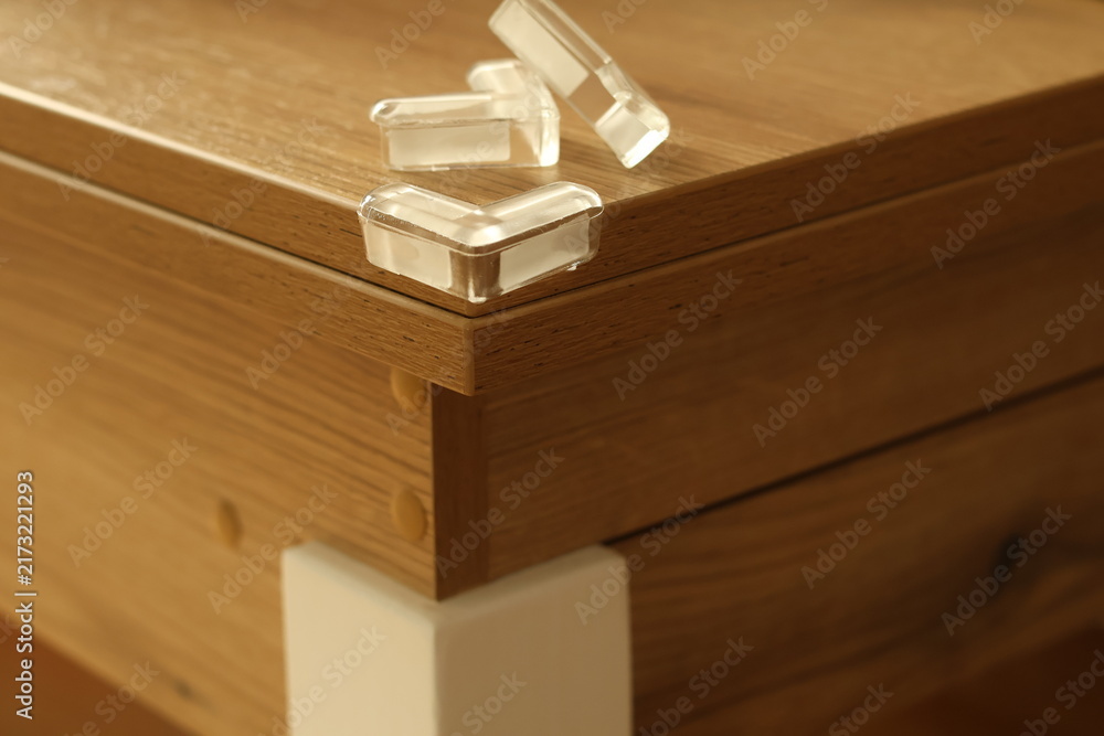 Fototapeta premium Soft protective corner guards are attached to sharp furniture edges to prevent child injuries. The image highlights toddler safety, household protection and simple measures used to reduce bumps and ac