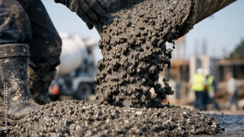 Close up of fresh wet concrete mix pouring from mixer chute at building construction site