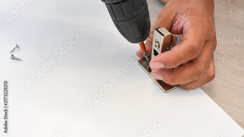 Canvas Print Close-up of a carpenter's hand using an electric drill to screw a metal conceale