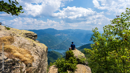Hiker on Rocky Cliff Above Mountain Valley