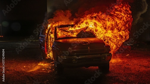 View of a pickup truck engulfed in intense flames at night, with bright fire illuminating the dark surroundings in Lindenhurst, New York, United States.