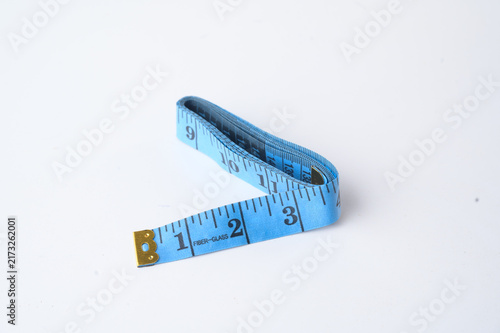 A blue flexible measuring tape laid out on a white surface, showing measurements in inches.