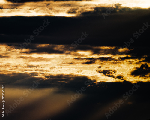 Quadro su tela Golden crepuscular rays streaming through thick dark storm clouds