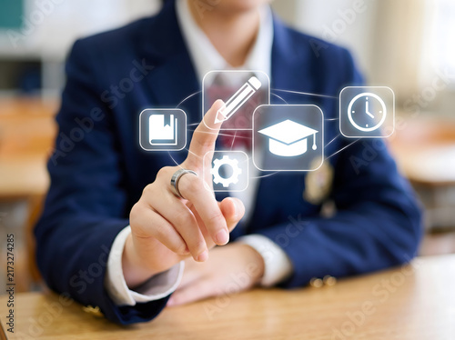 High school student in uniform using interactive digital screen interface with education icons for e-learning, online studies, and modern technology