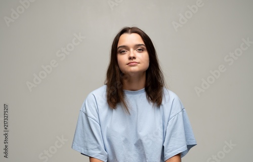 Fotografie Young woman portrait in studio, brown hair and blue tee, calm confident gaze, mi