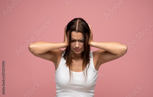 Quadro su tela Young woman suffering from headache, covering ears with hands, feeling pain and