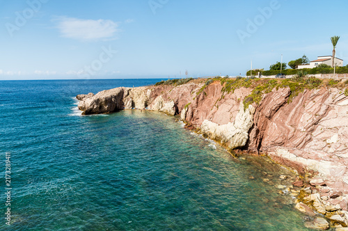 Striking red cliff at Cala Maidduzza in Terrasini, province of Palermo, Sicily, Italy, overlooking the Mediterranean Sea.
