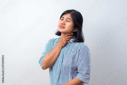Foto Young woman rubs her throat, appearing uncomfortable