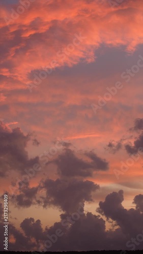 Colorful orange and pink clouds drifting across the sky at sunset