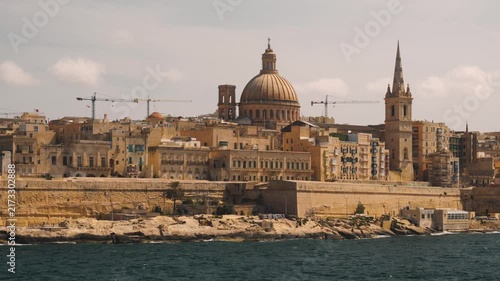Serene maltese coastal cityscape with cathedral domes and tall spires in valletta. wide-angle shot 