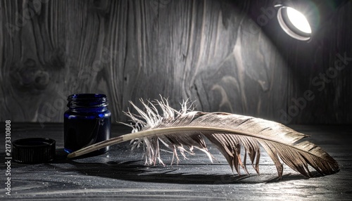 A delicate feather quill rests beside a vintage blue ink bottle on a dark wooden surface, evoking a sense of classic writing and historical inspiration.