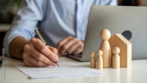 Man signing home insurance or mortgage contract with wooden family figures