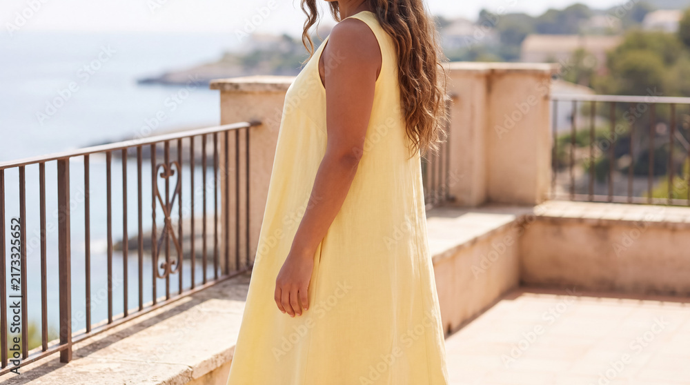 Naklejka premium Woman enjoying coastal resort balcony view on vacation, wearing a breezy yellow summer dress