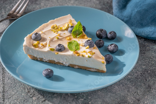 Creamy Mascarpone Cheesecake Slice Served With Blueberries Pistachios Maple Syrup And Mint Leaves