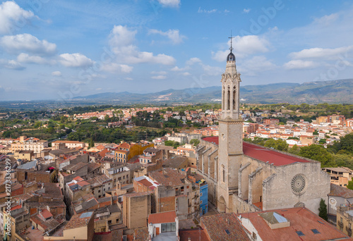 Obraz na płótnie The Campanar de Valls, a Gothic bell tower with tracery windows and a rose window, rises above the old town of Valls, Spain, with a valley and mountains visible in the distance