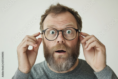 Surprised man adjusting glasses with wide eyes